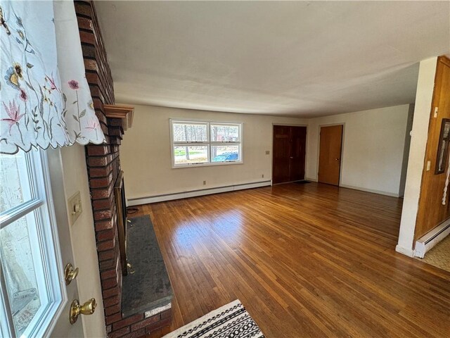 unfurnished living room with a fireplace, baseboards, baseboard heating, and wood finished floors