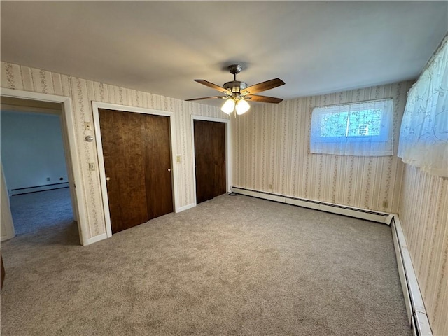 unfurnished bedroom featuring carpet, multiple closets, baseboard heating, and wallpapered walls
