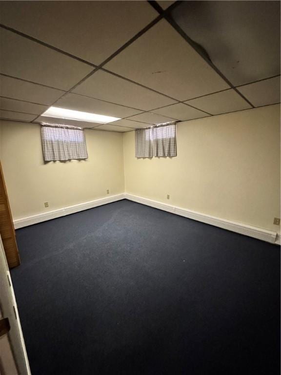 finished basement featuring baseboards, a drop ceiling, and dark colored carpet