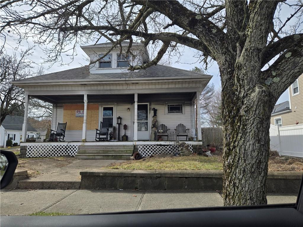 bungalow with a porch, fence, and roof with shingles