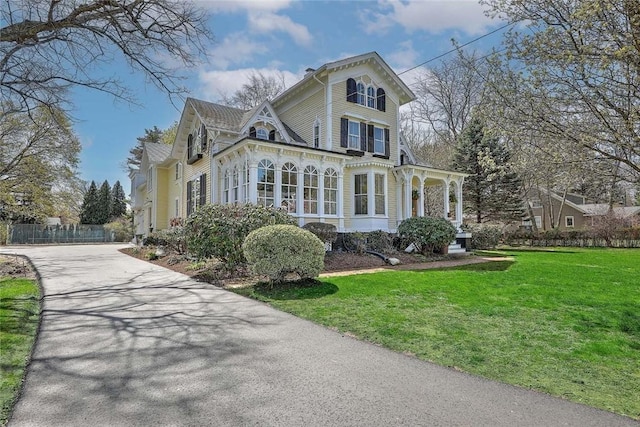 view of front facade featuring fence, a front lawn, and concrete driveway
