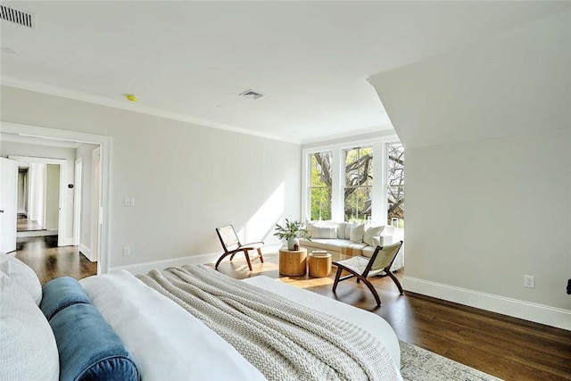 bedroom with baseboards, visible vents, ornamental molding, and wood finished floors