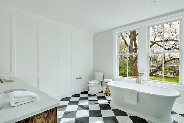 bathroom featuring a freestanding tub, a decorative wall, and toilet