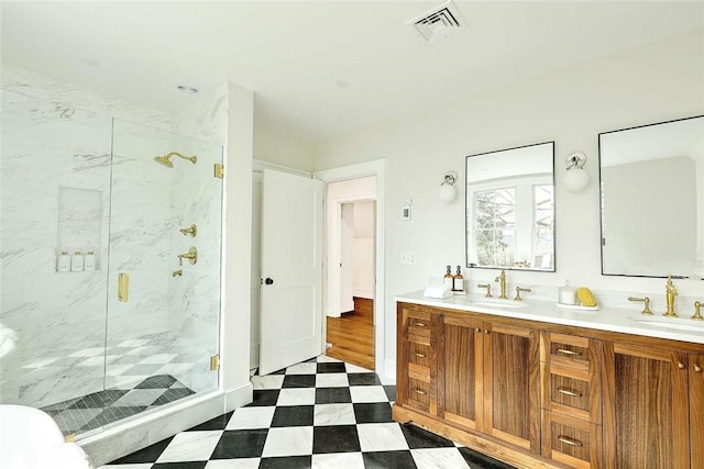 bathroom with a marble finish shower, a sink, tile patterned floors, and visible vents