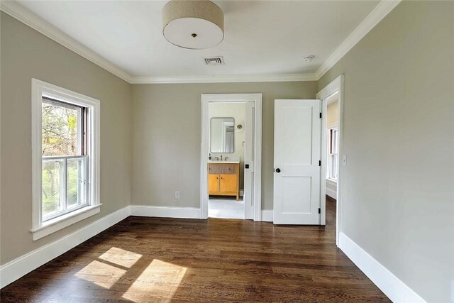 unfurnished bedroom featuring baseboards, visible vents, dark wood-style floors, and crown molding