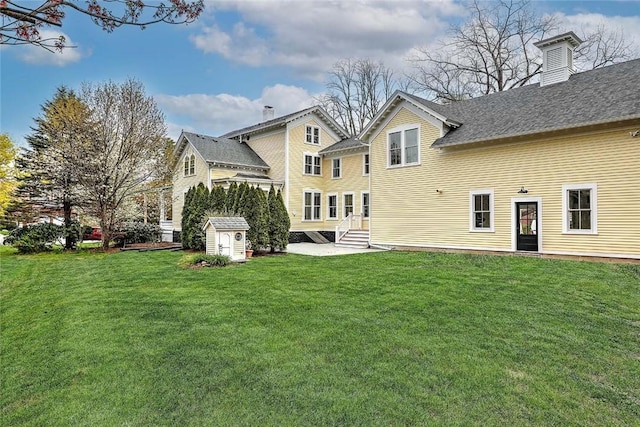 rear view of house featuring a lawn, a patio, an outbuilding, and a storage shed