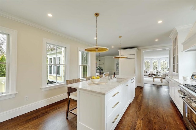 kitchen featuring ornamental molding, a kitchen bar, white cabinets, and a sink