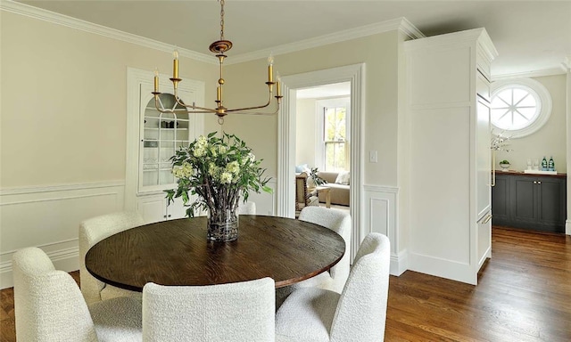 dining area with wood finished floors, a healthy amount of sunlight, ornamental molding, and wainscoting