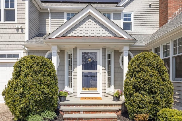 entrance to property with a garage and roof with shingles