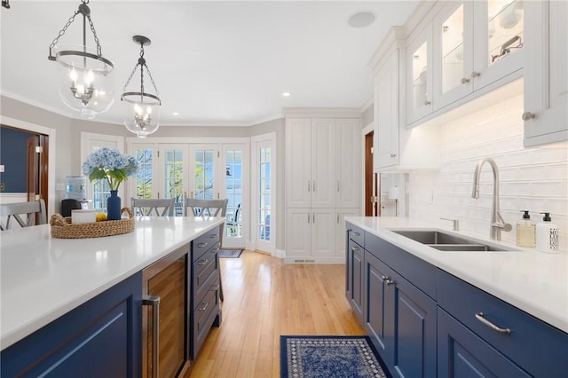 kitchen with blue cabinetry, backsplash, a sink, and light countertops