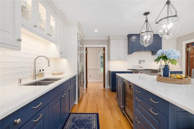 kitchen with blue cabinets, white cabinetry, a sink, and light countertops