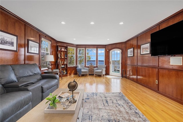 living area featuring crown molding, light wood finished floors, and wooden walls