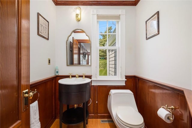 bathroom featuring wainscoting, visible vents, wood walls, and toilet