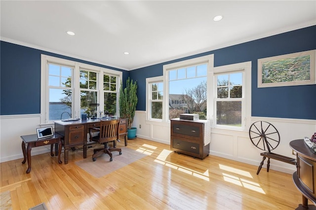 office area with a decorative wall, ornamental molding, a wainscoted wall, and light wood finished floors