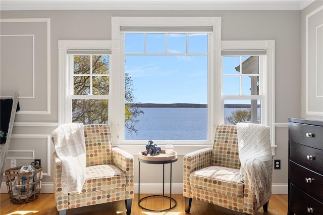 living area with wood finished floors, a water view, and ornamental molding