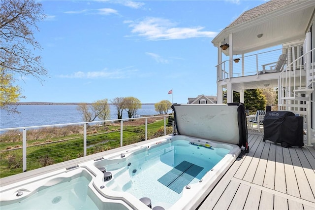 view of pool featuring stairway, a deck with water view, a grill, and hot tub deck surround