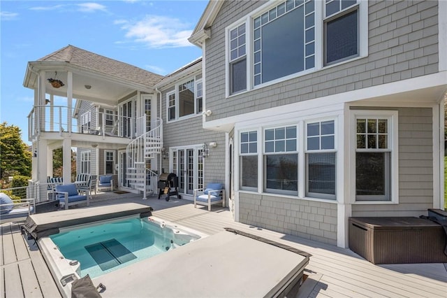 rear view of property featuring a pool, a wooden deck, hot tub deck surround, and a shingled roof