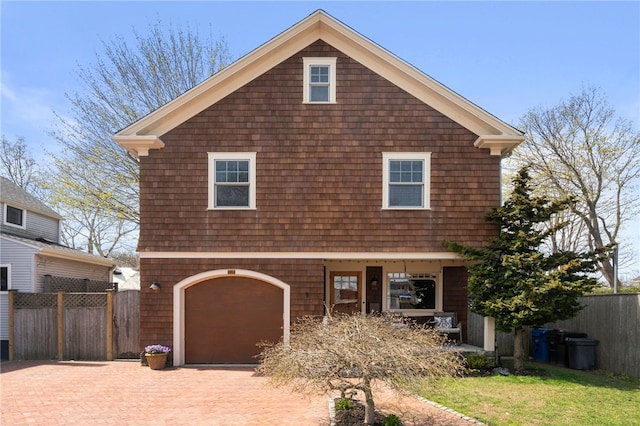 view of front facade featuring a garage, fence, and decorative driveway