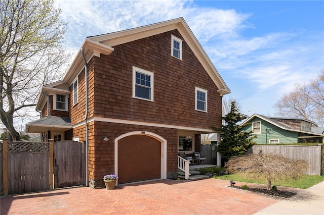 view of front of property with fence, decorative driveway, and a garage