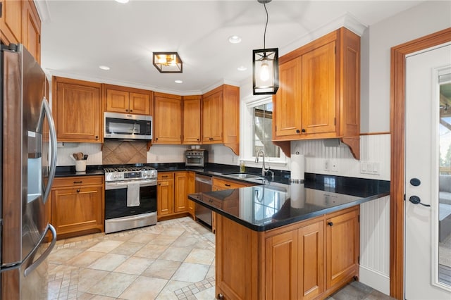 kitchen featuring a peninsula, appliances with stainless steel finishes, brown cabinets, and a sink