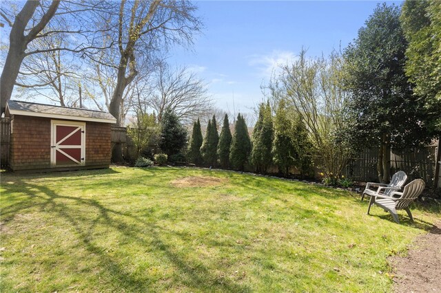 view of yard with a fenced backyard, a storage unit, and an outdoor structure