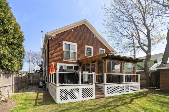 rear view of house with a lawn, a fenced backyard, a sunroom, and a wooden deck