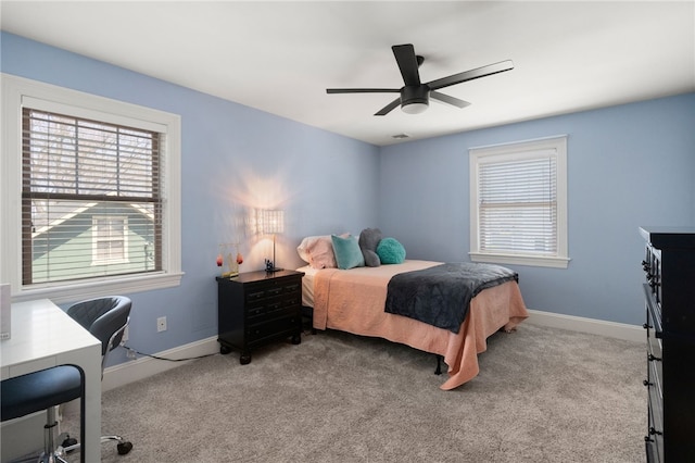 carpeted bedroom featuring a ceiling fan, baseboards, and multiple windows