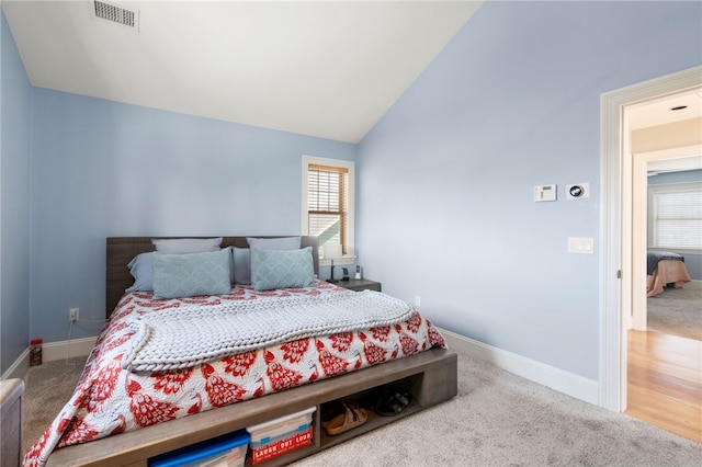 carpeted bedroom featuring baseboards, lofted ceiling, multiple windows, and visible vents