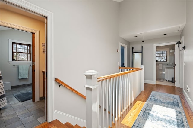 hall featuring radiator heating unit, wood finished floors, baseboards, and an upstairs landing