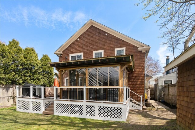 rear view of property with a wooden deck, a sunroom, fence, and a yard