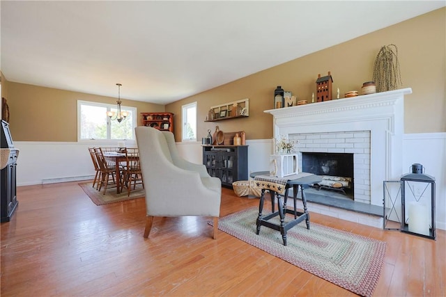 living room with light wood-type flooring, a fireplace, a chandelier, and a baseboard radiator