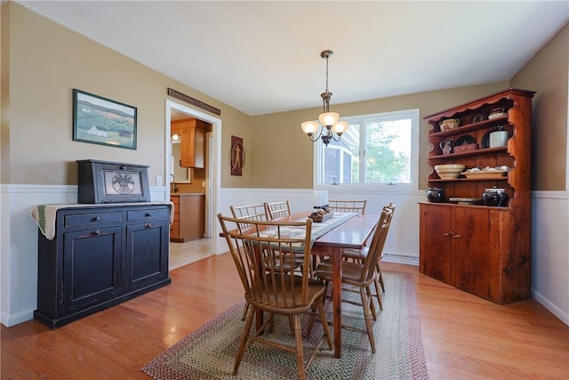 dining room featuring light wood-type flooring, a wainscoted wall, a chandelier, and baseboard heating