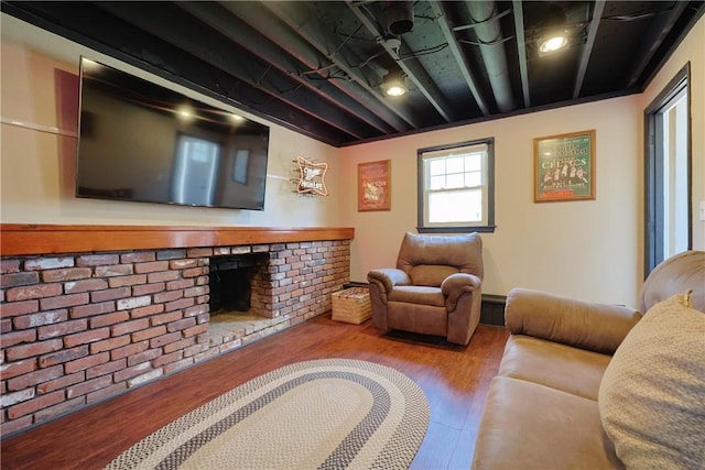living room with wood finished floors and a brick fireplace
