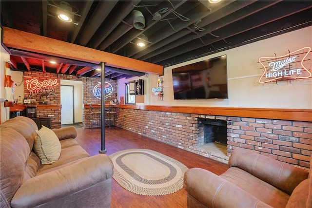 living area with brick wall, a brick fireplace, and wood finished floors