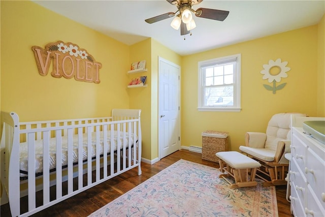 bedroom featuring baseboards, wood finished floors, a nursery area, and ceiling fan