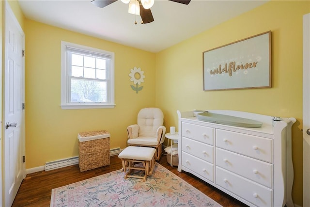 sitting room featuring baseboard heating, ceiling fan, baseboards, and dark wood-type flooring