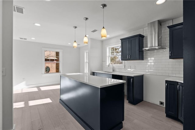kitchen featuring visible vents, backsplash, wall chimney exhaust hood, and a sink