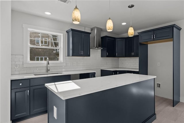kitchen featuring wall chimney exhaust hood, decorative backsplash, decorative light fixtures, and a sink