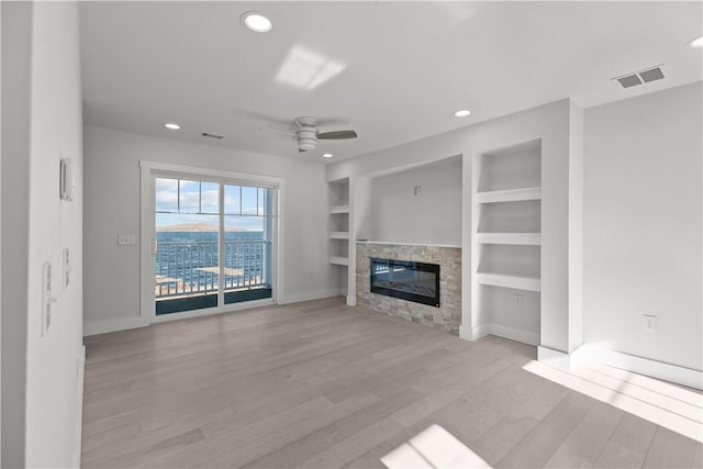 unfurnished living room featuring recessed lighting, wood finished floors, visible vents, a fireplace, and built in features