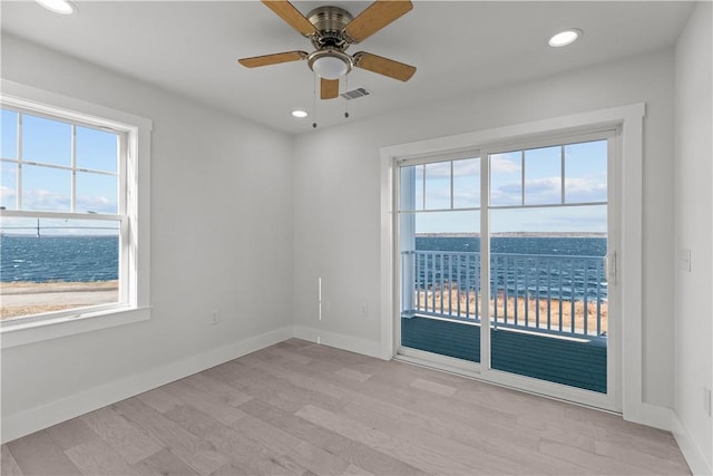 spare room featuring light wood-style flooring, visible vents, and a healthy amount of sunlight