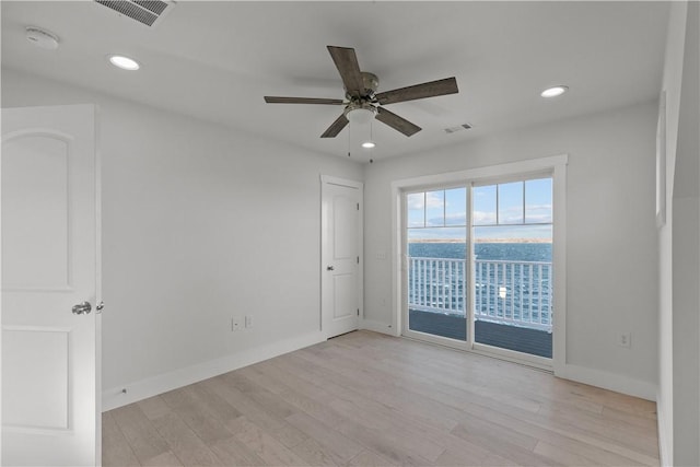 unfurnished room featuring light wood-type flooring, a ceiling fan, and visible vents