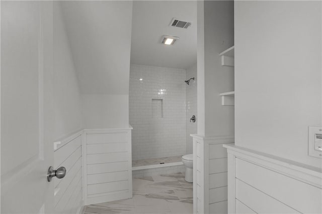 bathroom with marble finish floor, a tile shower, toilet, and visible vents