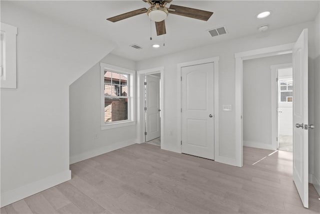 unfurnished bedroom featuring baseboards, multiple windows, light wood-style floors, and visible vents