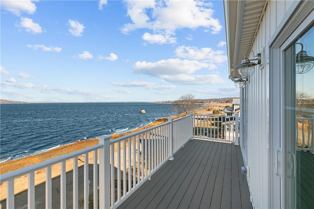wooden terrace featuring a view of the beach and a water view
