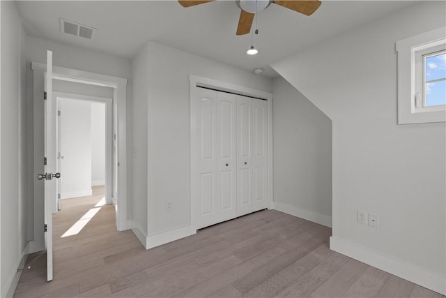 additional living space featuring light wood-type flooring, visible vents, a ceiling fan, and baseboards