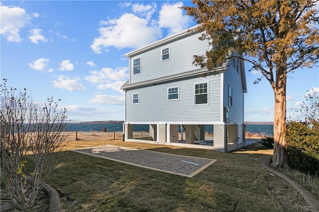 back of property with a lawn and a water view