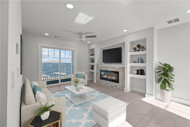 living room featuring a glass covered fireplace, visible vents, recessed lighting, light wood-style floors, and a ceiling fan