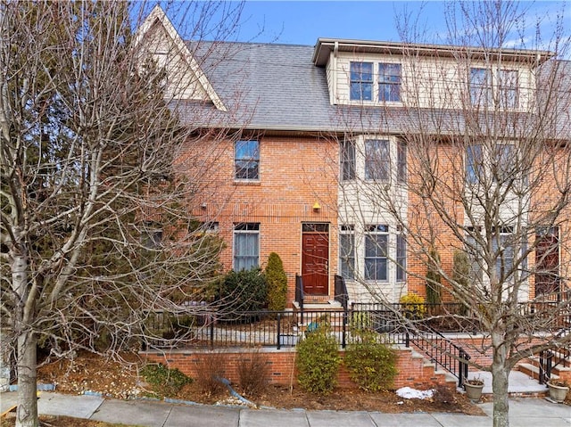 view of front facade featuring brick siding and roof with shingles