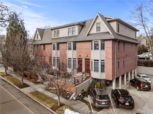 view of front of property featuring a shingled roof and brick siding