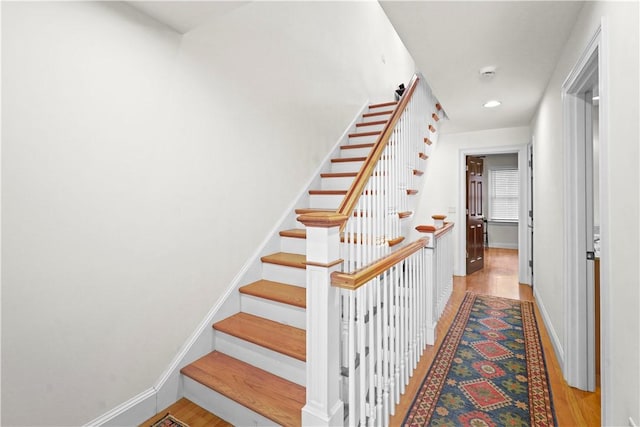 staircase featuring baseboards, wood finished floors, and recessed lighting